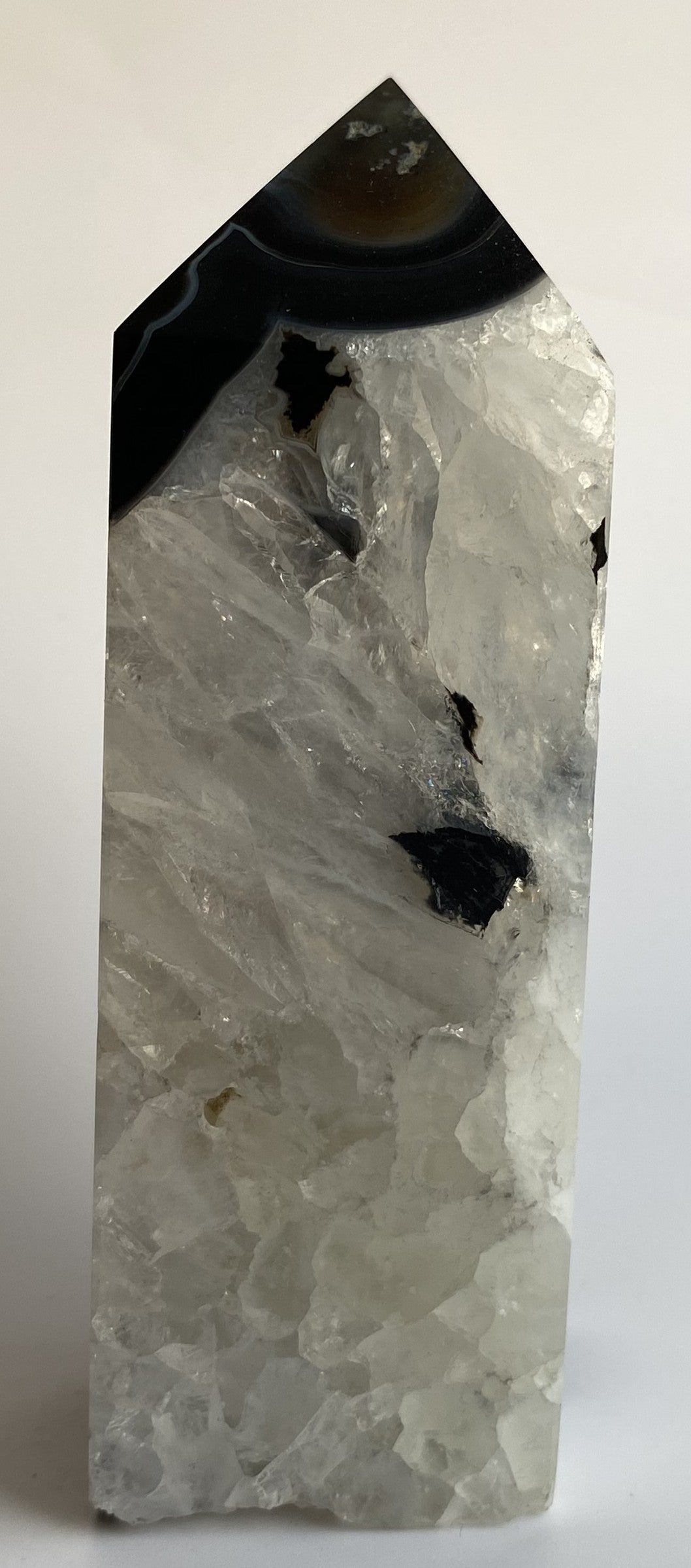 Obelisc din cristal de agat negru pe fundal alb sub lumina naturala