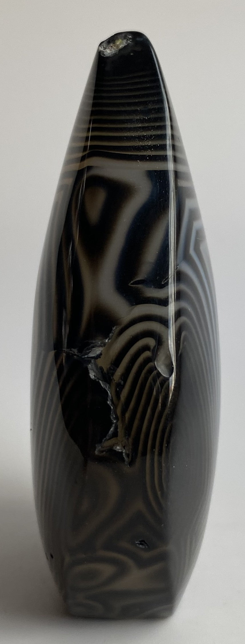 Sculptura din cristal de agat negru pe fundal alb sub lumina naturala