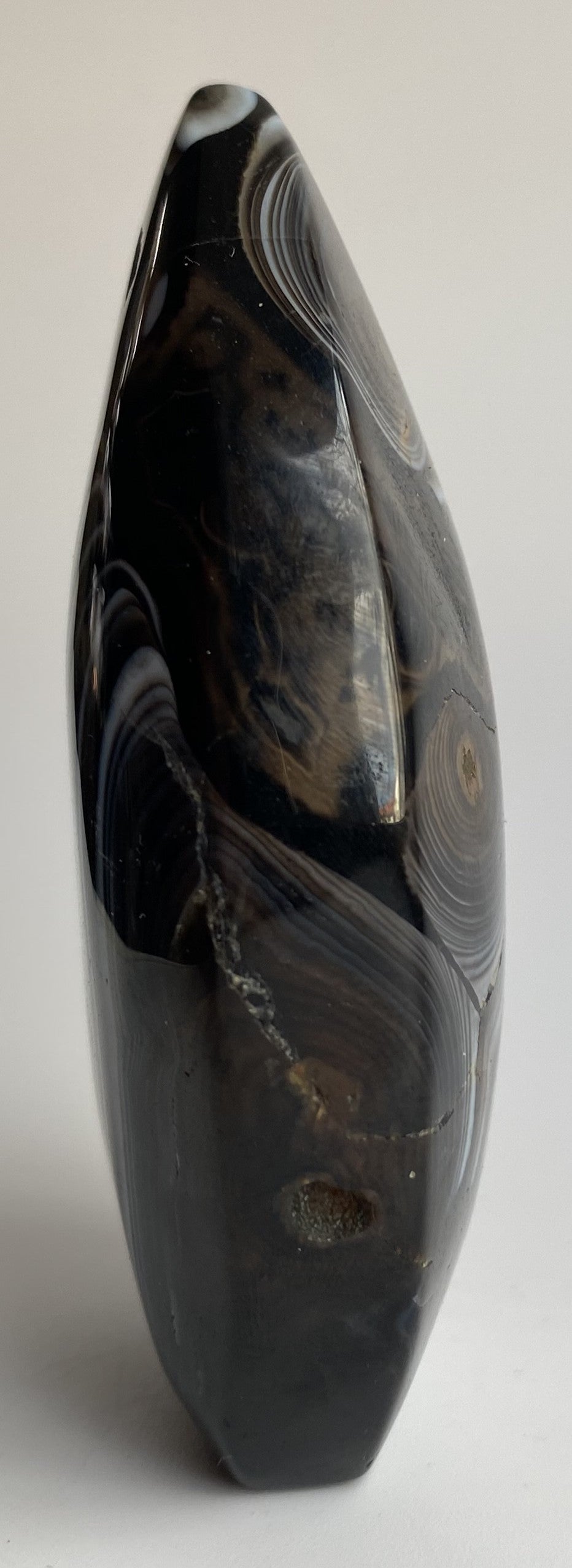 Sculptura din cristal de agat negru pe fundal alb sub lumina naturala