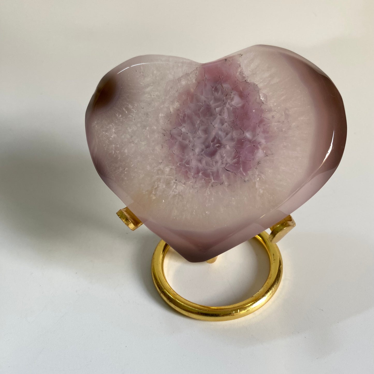 Inima din agat roz pe suport metalic auriu pe fond alb sub lumina naturala