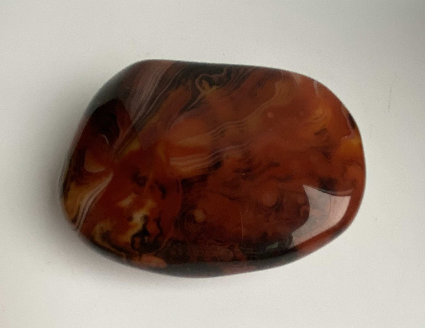 Polished Agat Sardonyx stone with rich brown and orange swirls on a white background