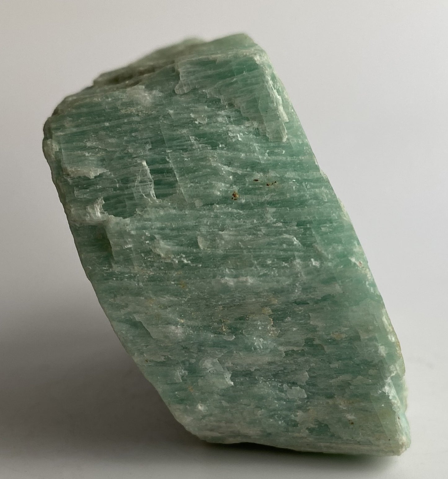 Piatra bruta din mineral de amazonit pe fundal alb sub lumina naturala