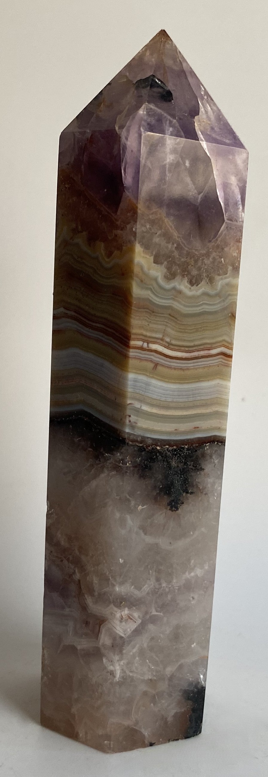 Obelisc din mineral simbiot de agat si ametist pe fundal alb sub lumina naturala