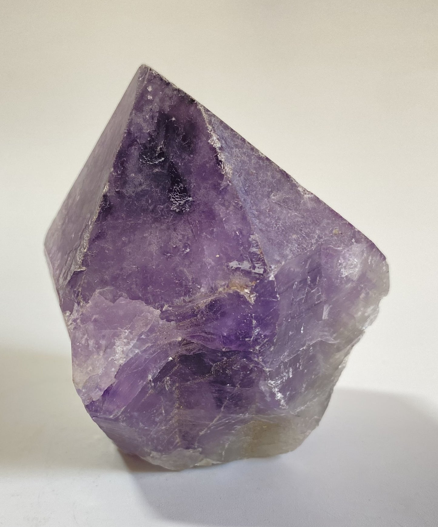 Varf brut din cristal de ametist pe fundal alb sub lumina naturala