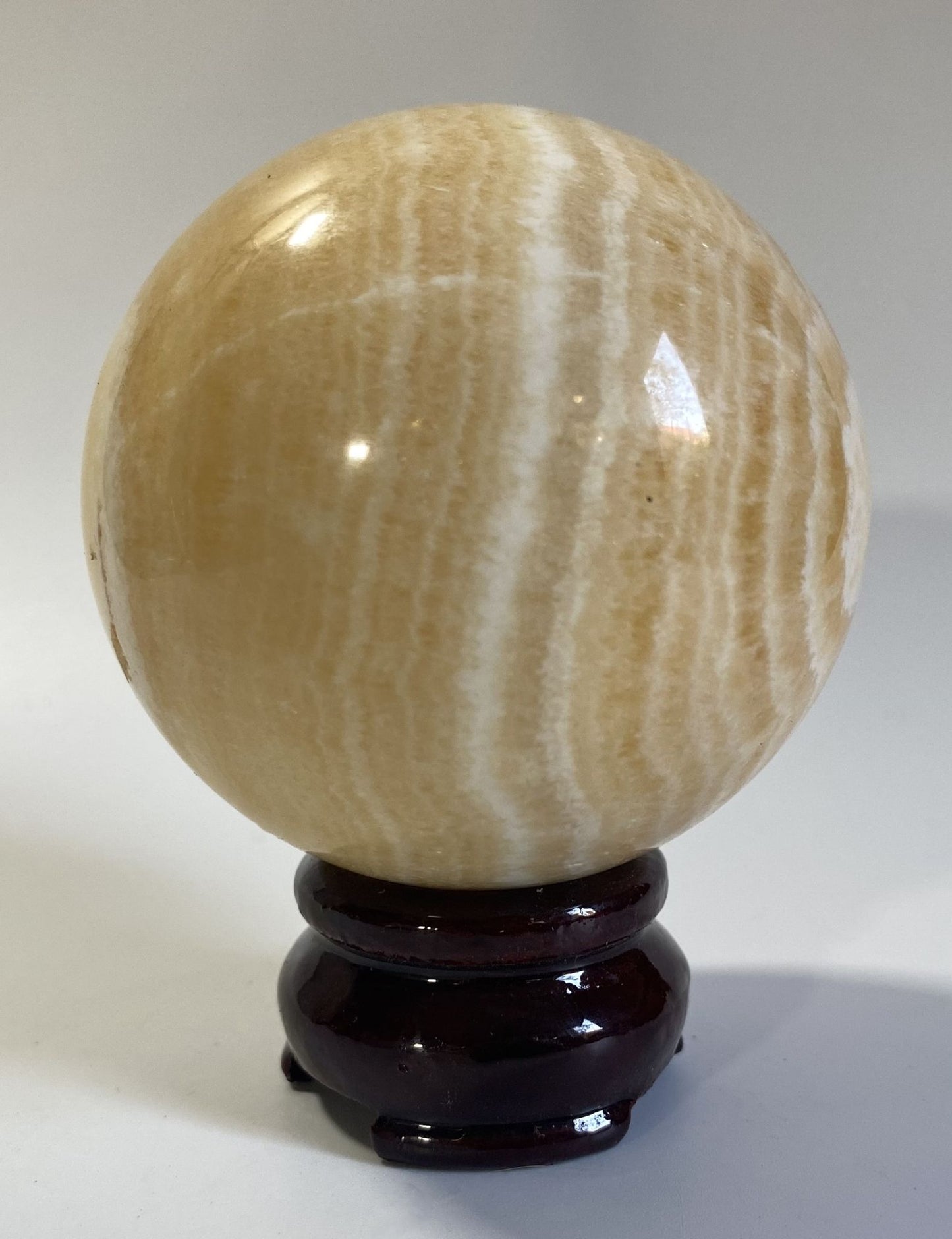 Sfera decorativa de 7.1cm din cristal de calcit galben pe suport din lemn cu fundal alb