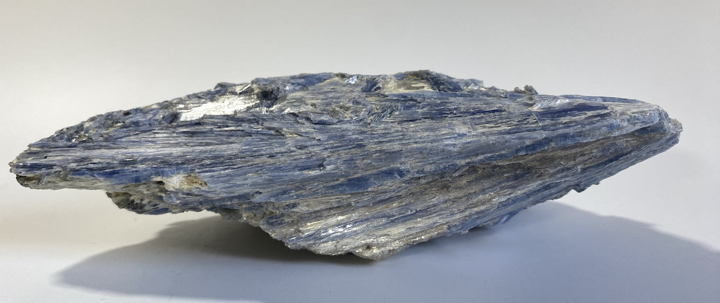 Piatra bruta din mineral de cianit pe fundal alb sub lumina naturala