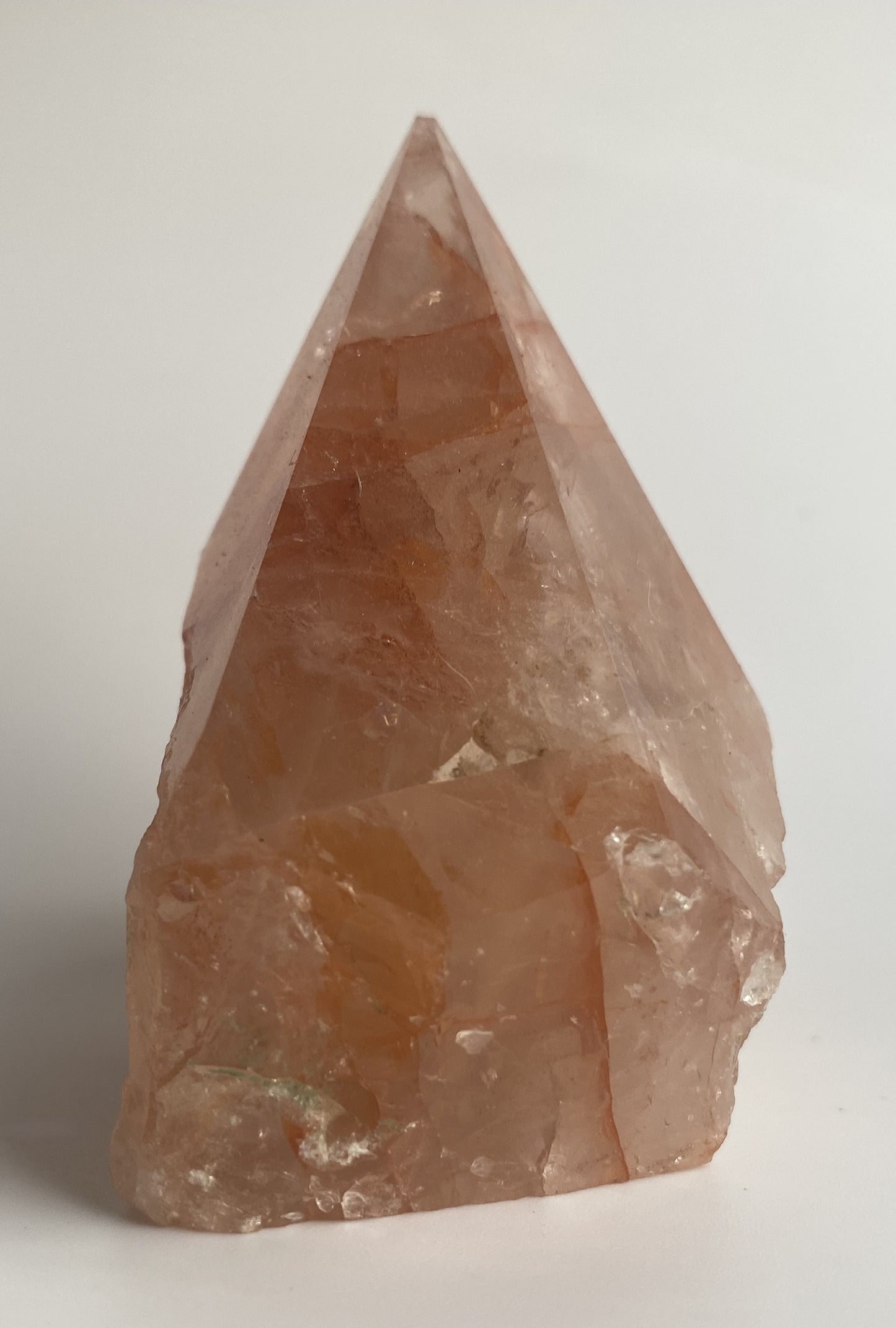 Varf polisat din cristal de cuart hematoid rosu pe fundal alb sub lumina naturala