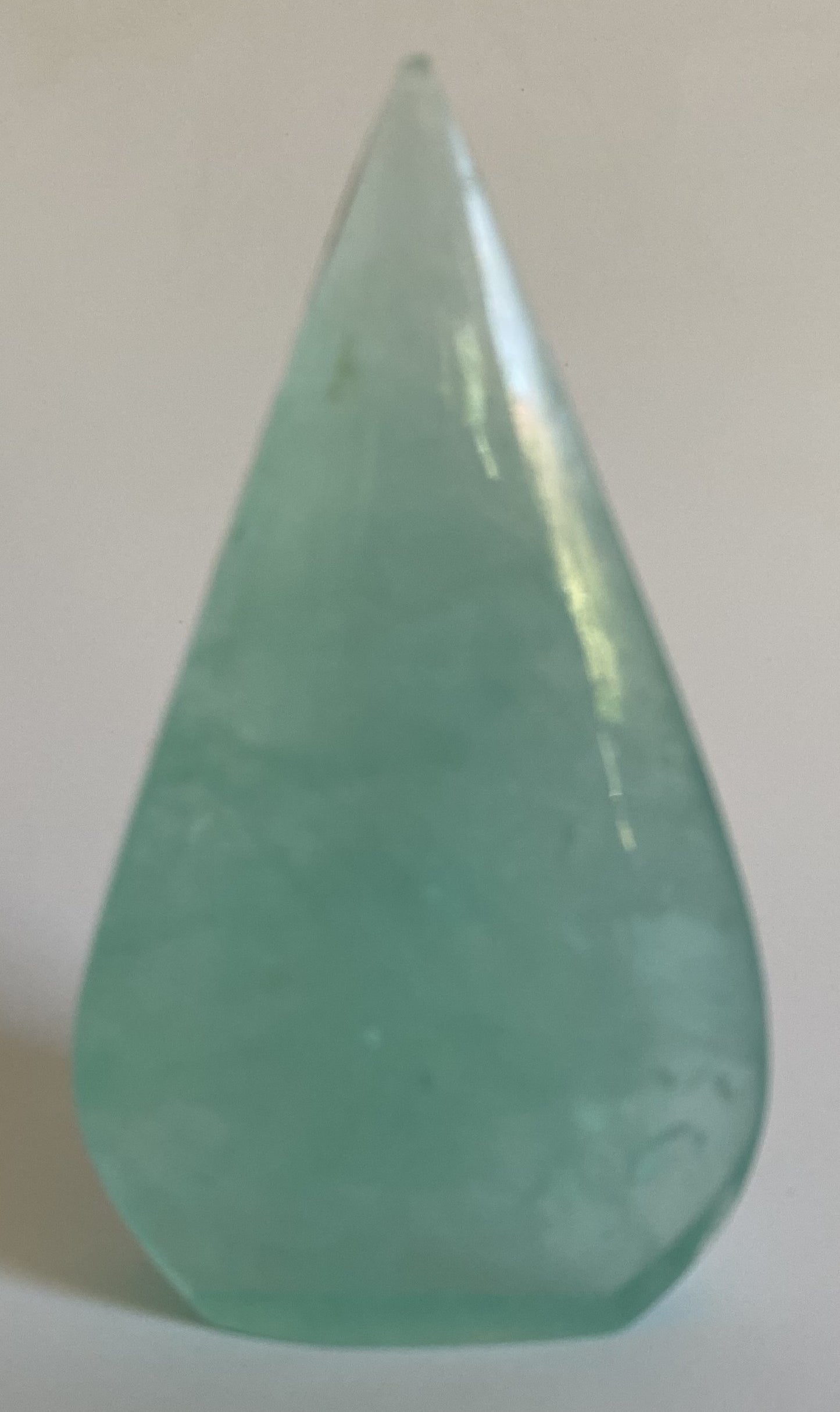 Sculptura din fluorit verde pe fundal alb sub lumina naturala