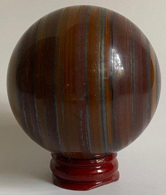 Sfera de 6.3cm din mineral de ochi de tigru cu fier pe suport din lemn cu fundal alb