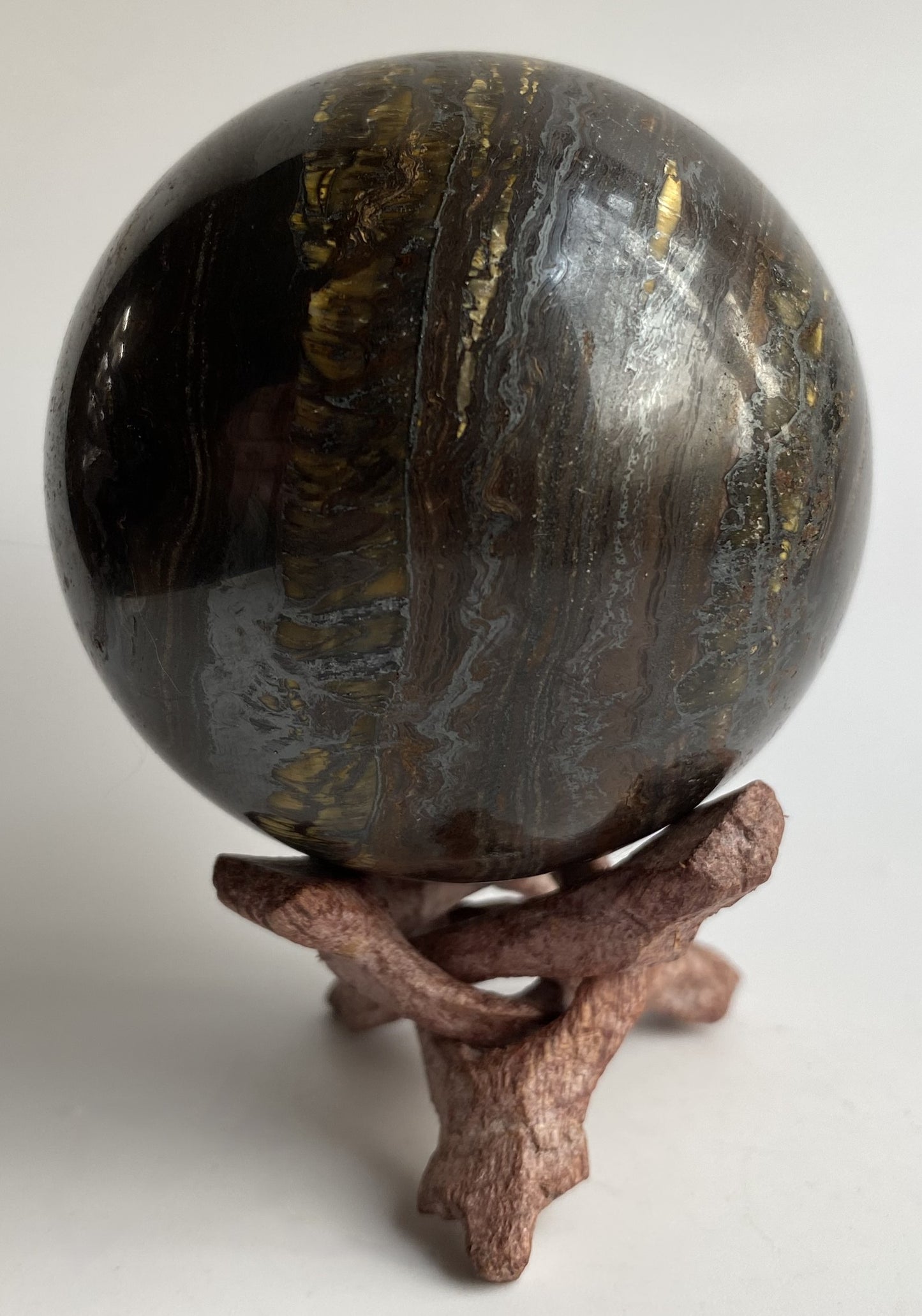 Sfera din ochi de tigru cu fier pe fond alb sub lumina naturala