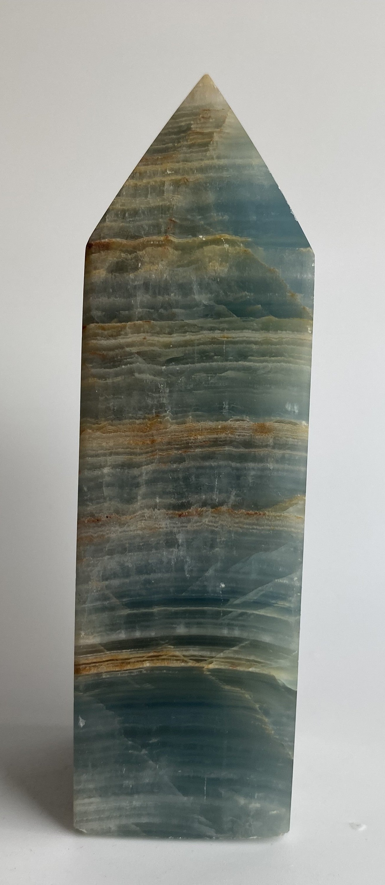 Obelisc din mineral de onix albasatru pe fundal alb sub lumina naturala