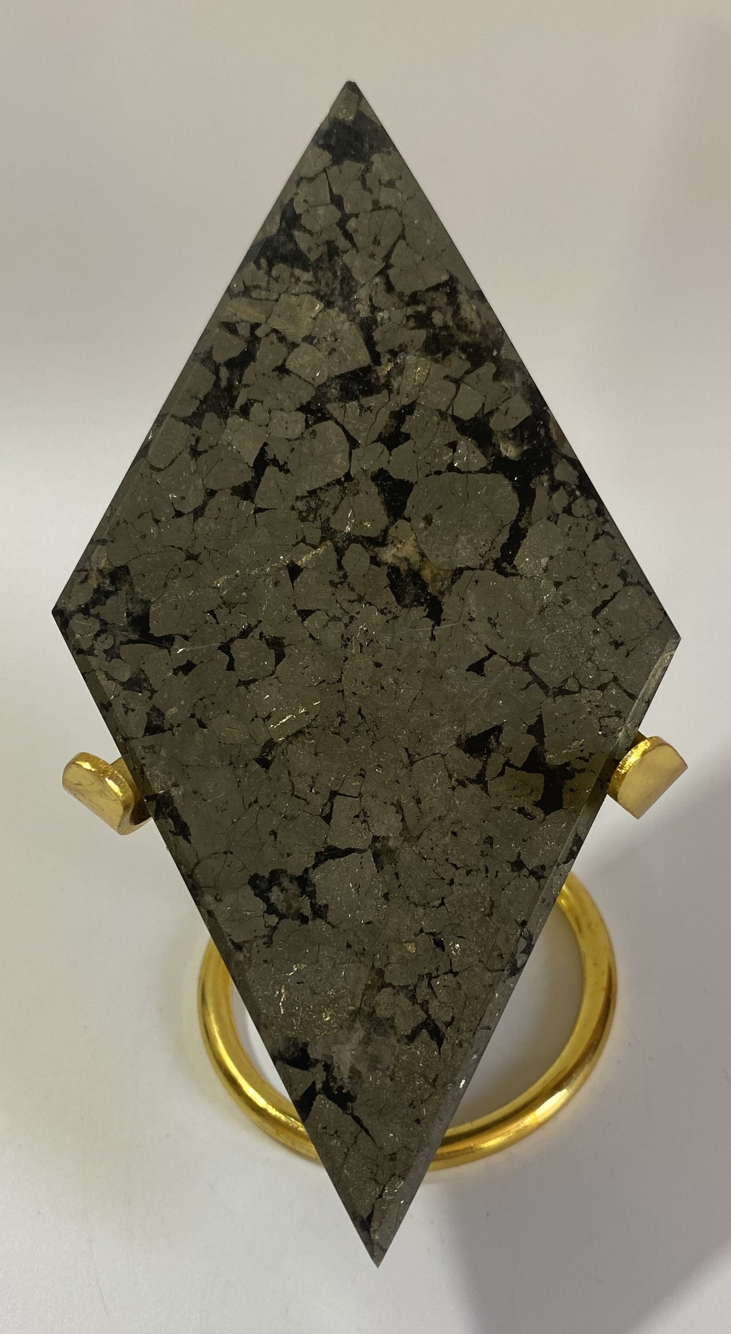 Romb din mineral de pirita cu suport metalic auriu pe fundal alb sub lumina naturala
