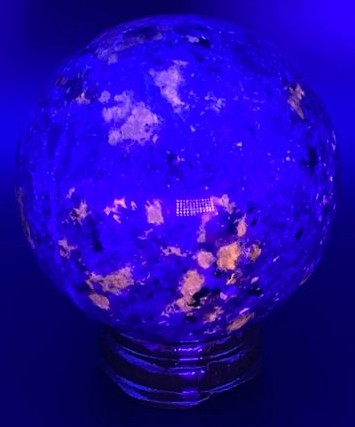 Sferă Yooperlite 5.4 cm cu suport din lemn sub lumina UV, piatră semiprețioasă naturală