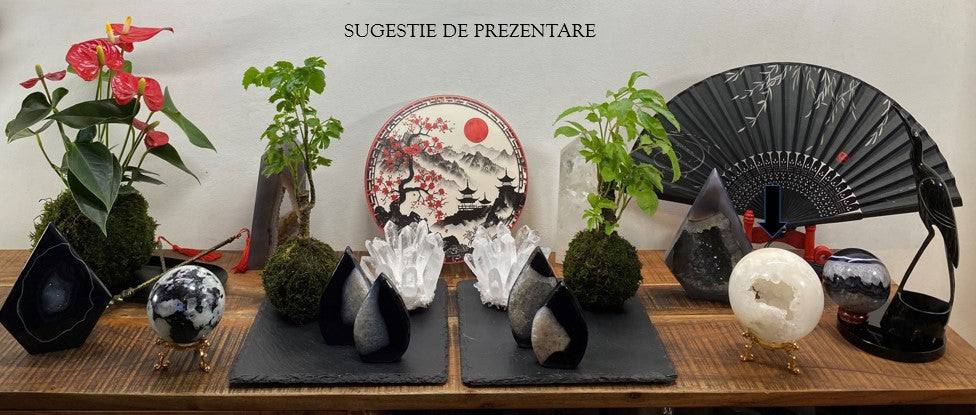Sfera din Cuart Alb pe suport metalic, expusa pe masa decorata cu plante si obiecte decorative asiatice