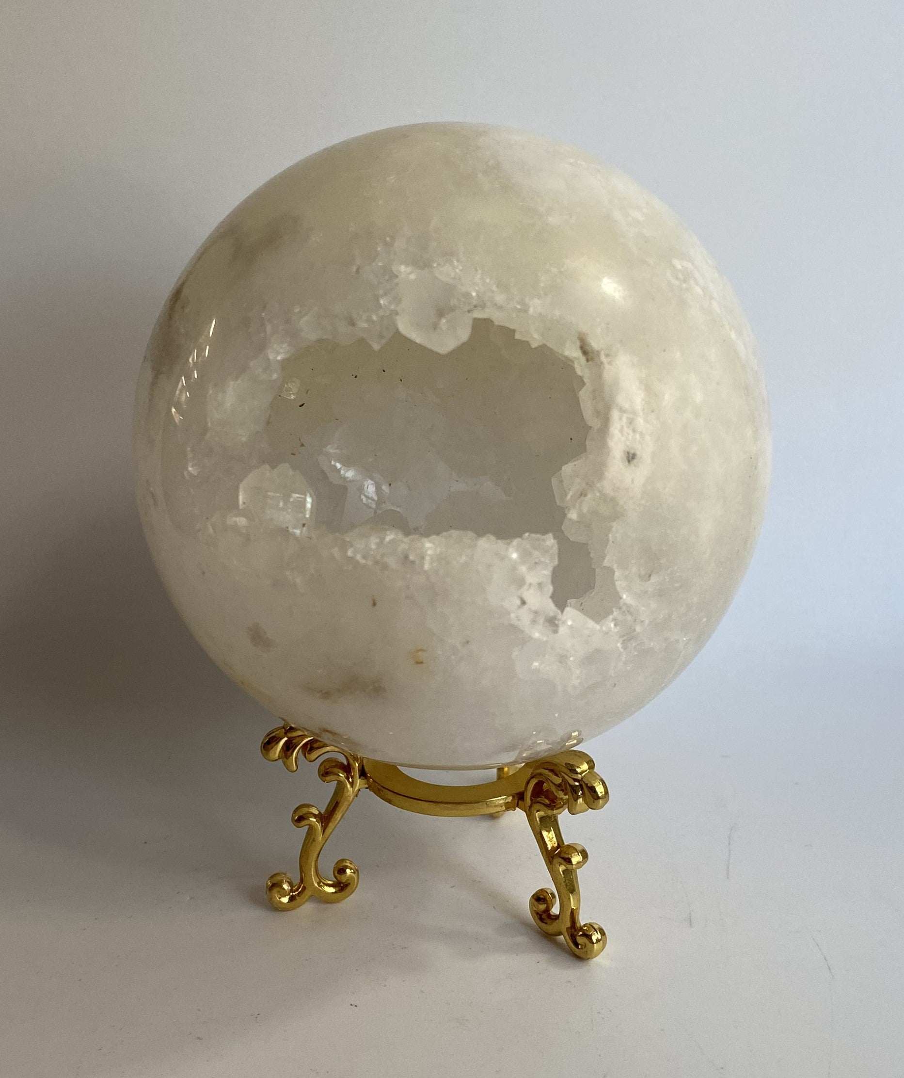 Cuart Alb spherical gemstone with metal stand on white background