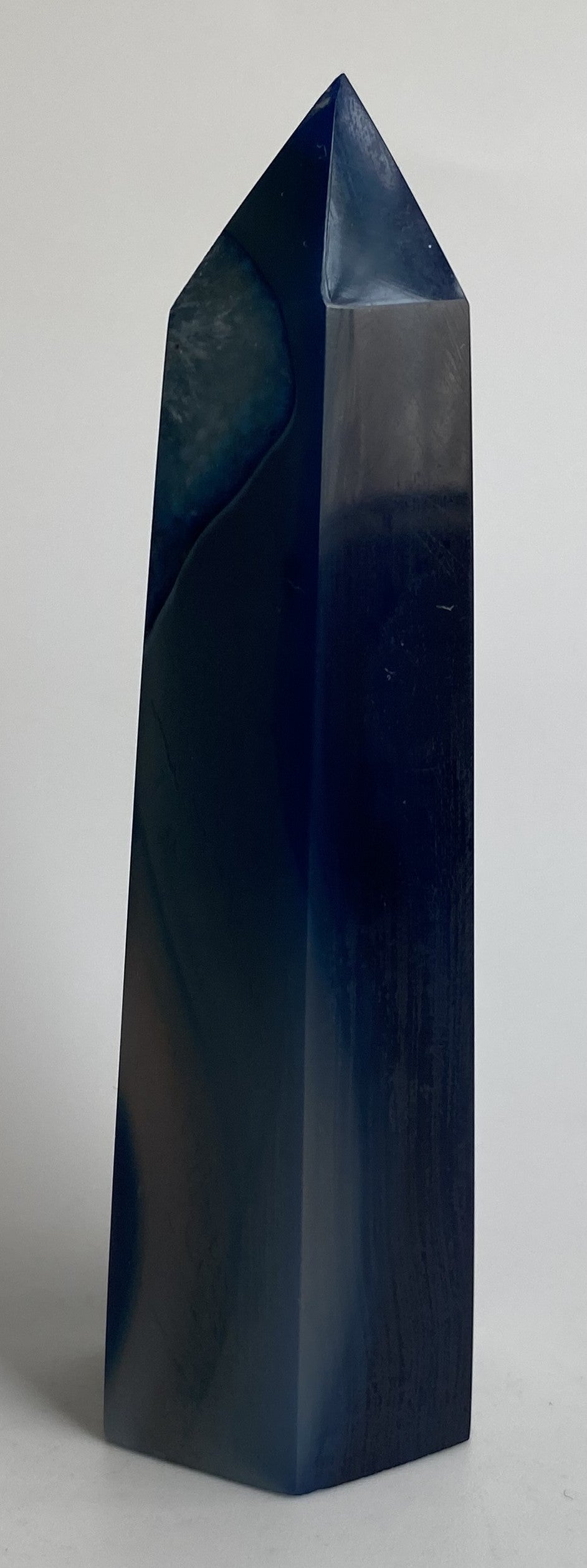 Obelisc din cristal de agat albastru pe fundal alb sub lumina naturala