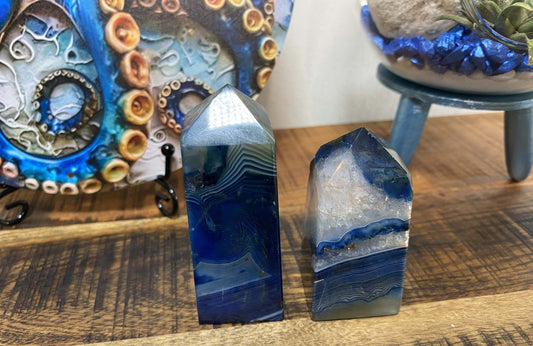 Set of two polished Agat Albastru obelisks with blue and white banded patterns on wooden surface