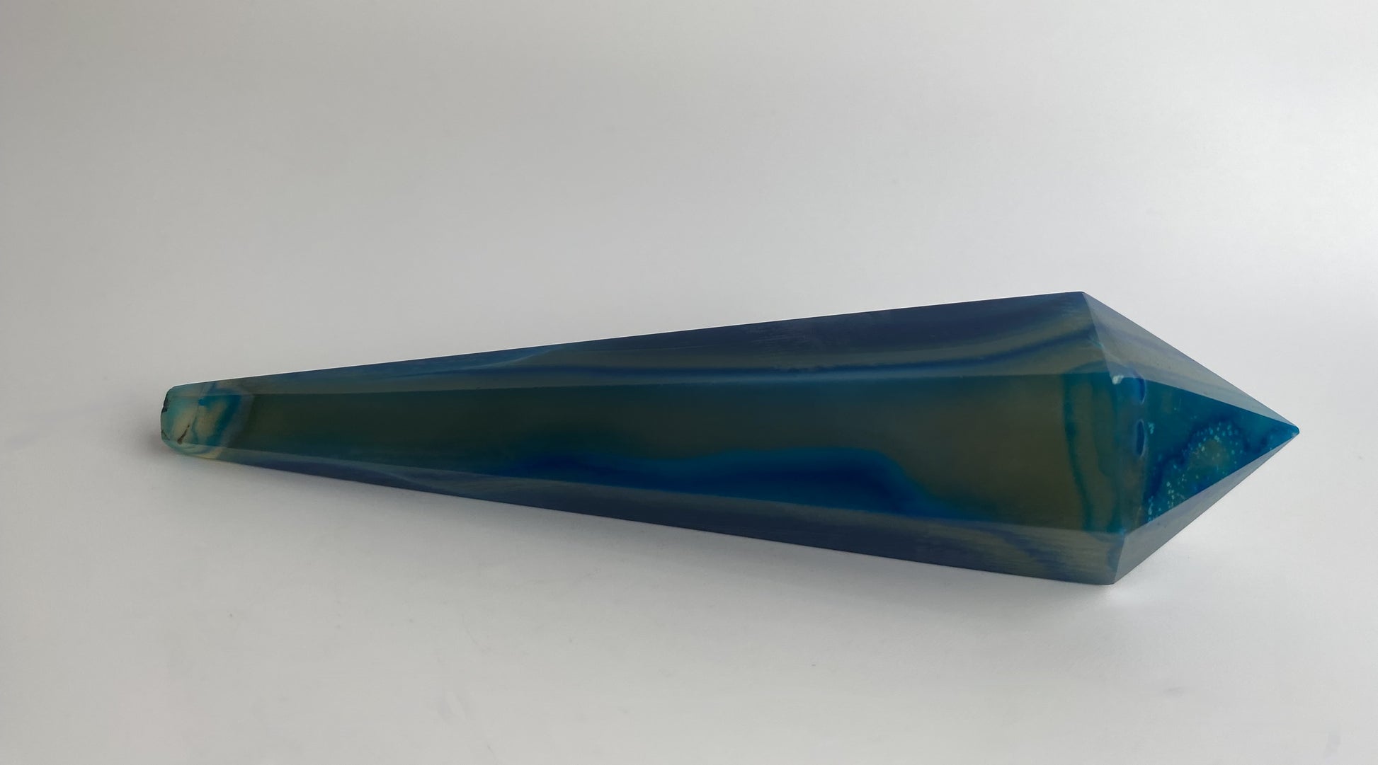Obelisc sceptru din cristal de agat albastru pe fundal alb sub lumina naturala