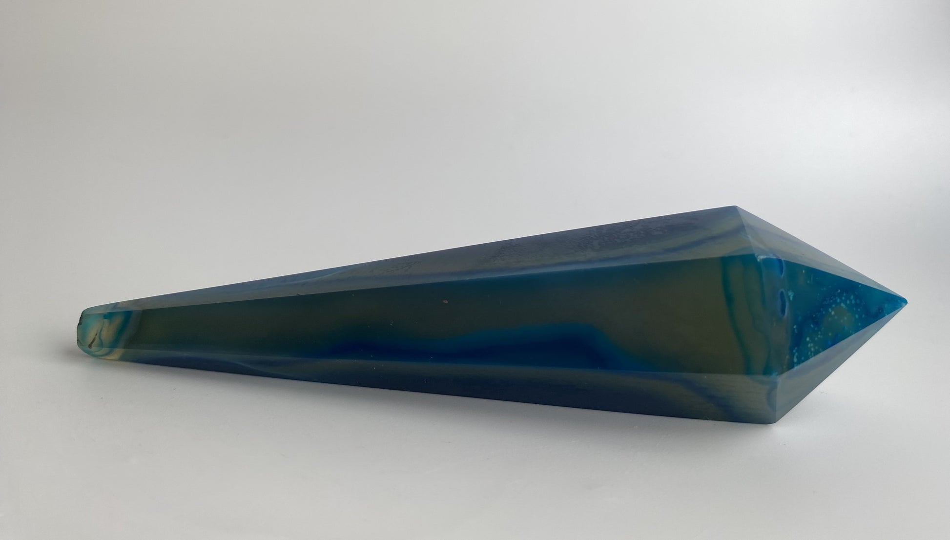 Obelisc sceptru din cristal de agat albastru pe fundal alb sub lumina naturala