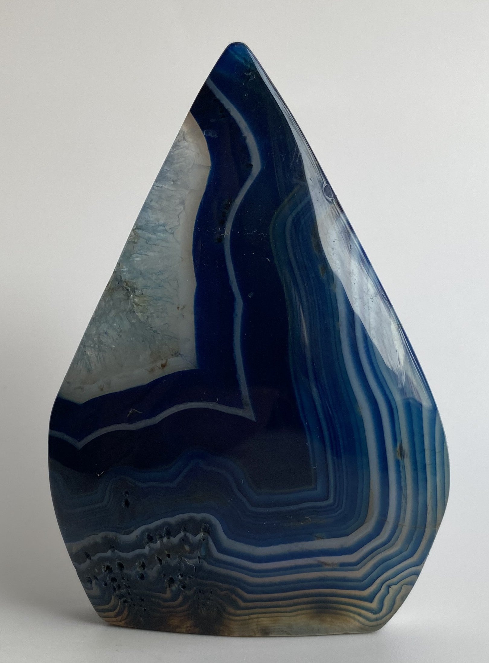 Sculptura din cristal de agat albastru pe fundal alb sub lumina naturala