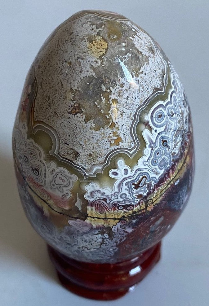 Ou yoni de 6.3cm din cristal de agat mexican pe suport din lemn cu fundal alb