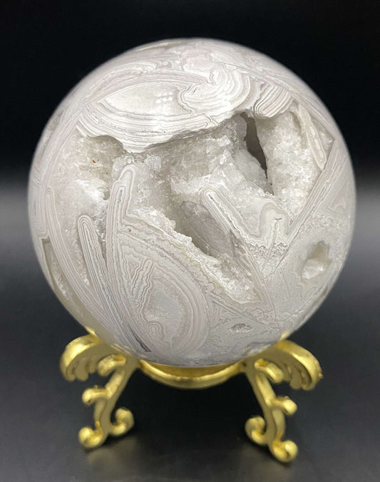 Sfera de Agat Mexican Alb cu suport metalic auriu pe fundal negru