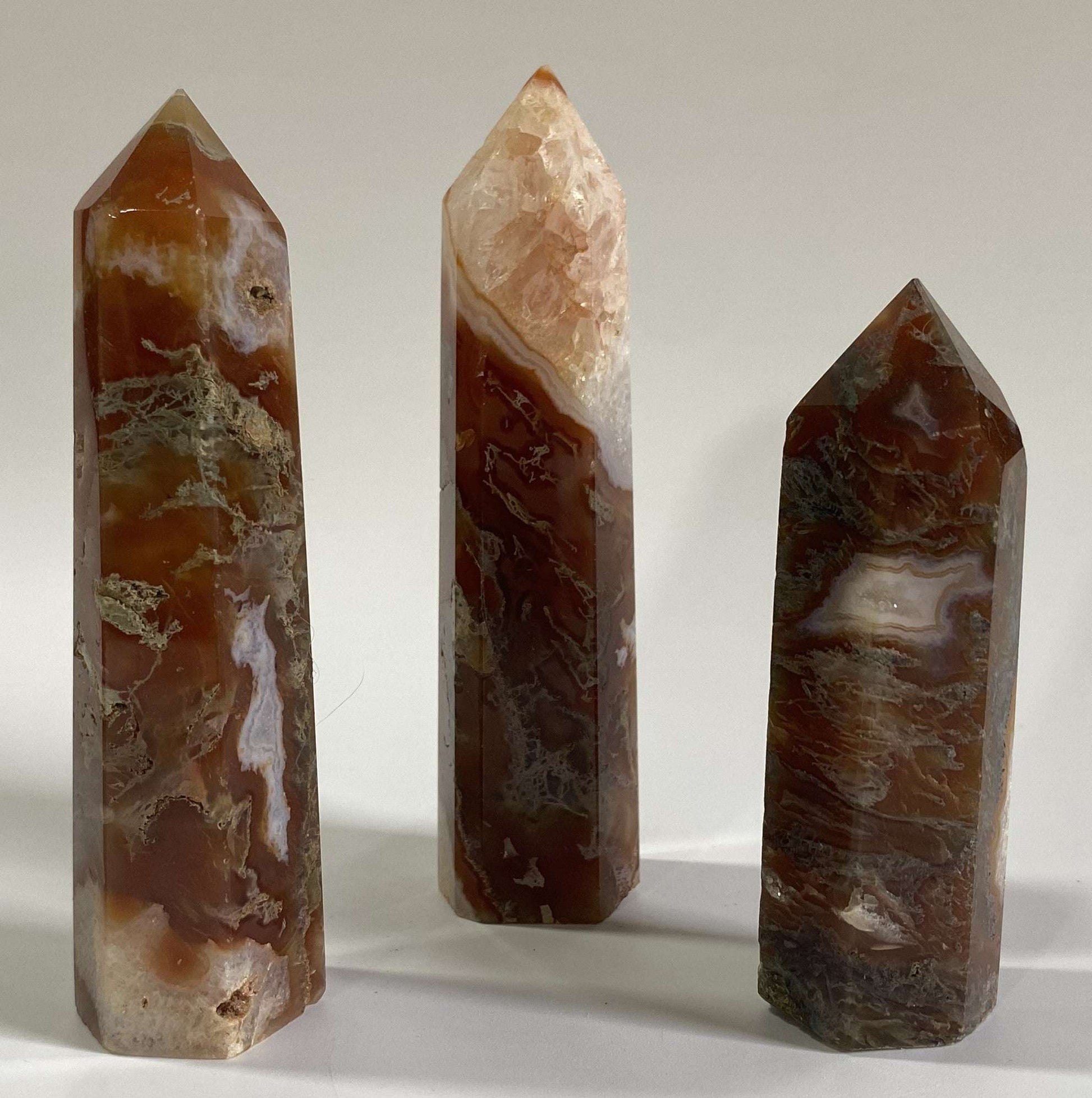 Set of three Agat Muschi Rosu semi-precious stone obelisks on white background
