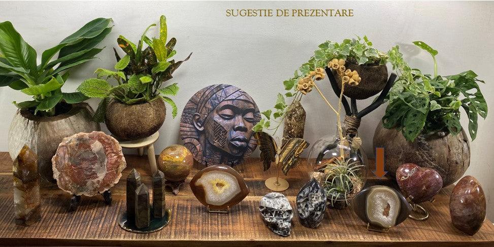 Natural Agat slice semiprecious stone with metal stand on wooden surface with plants and decorative items