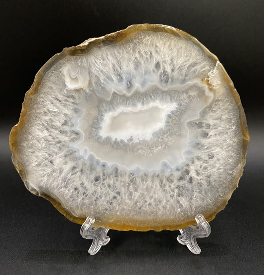 Felie din cristal de agat natural pe suport din plastic, cu fundal negru, sub lumina artificiala