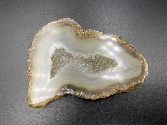 Felie de geoda din agat natural pe fond negru sub lumina artificiala