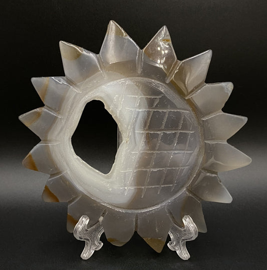 Sculptura sub forma de soare din cristal de agat natural cu geoda pe fundal negru sub lumina artificiala