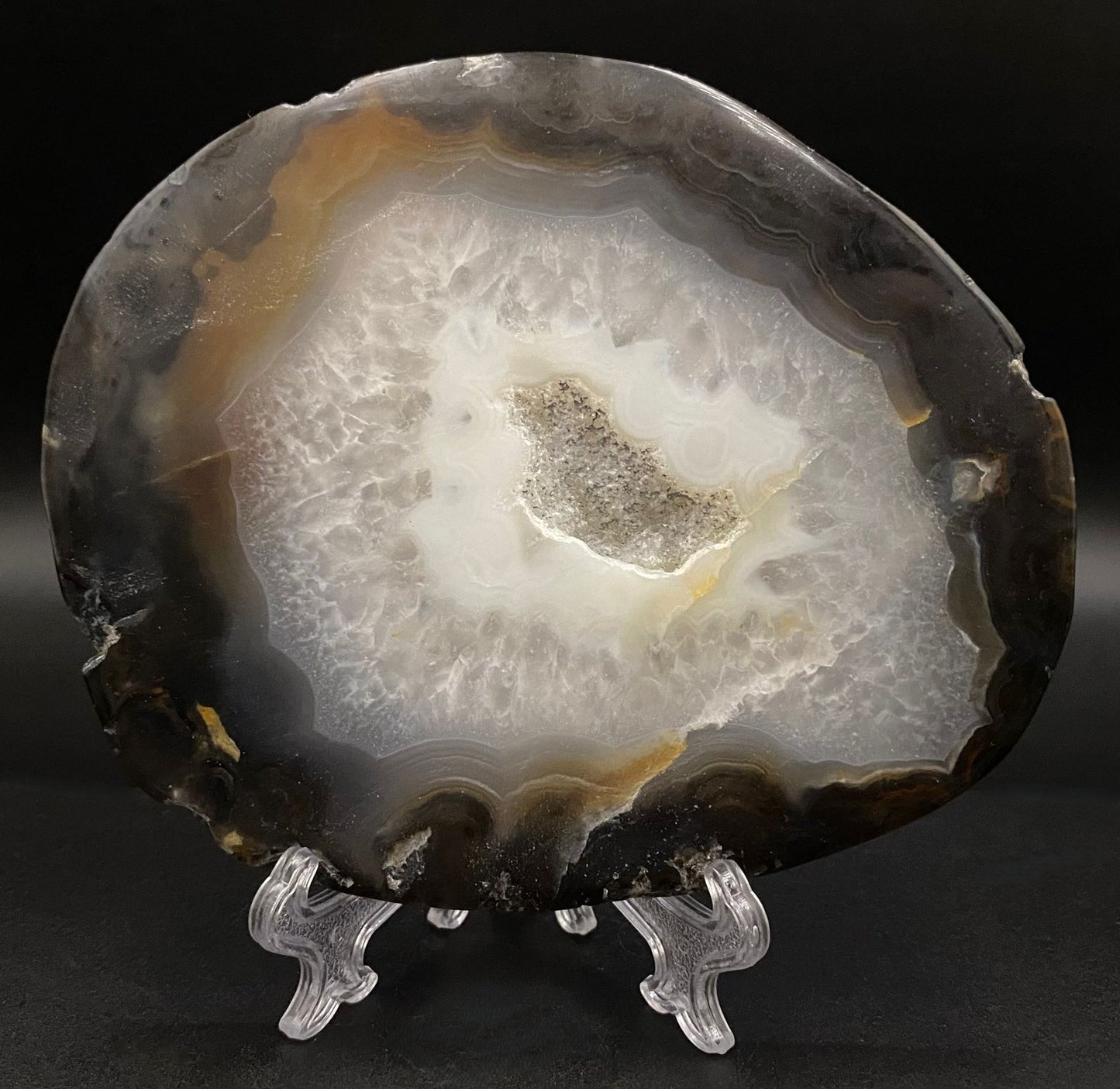 Felie de geoda de agat negru pe fond negru sub lumina artificiala