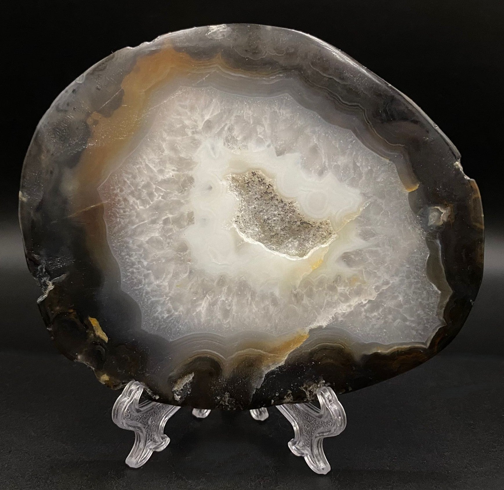 Felie de geoda de agat negru pe fond negru sub lumina artificiala