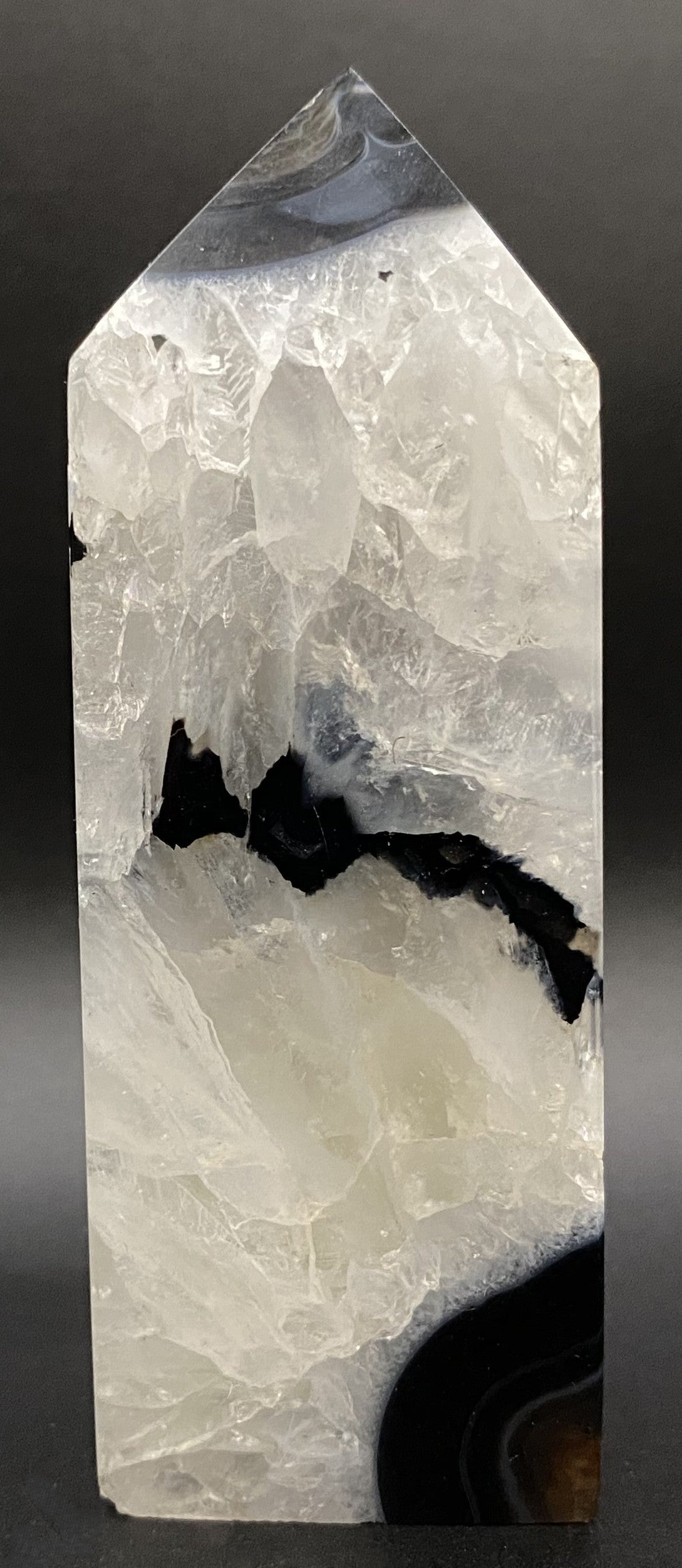 Obelisc din cristal de agat negru pe fundal negru sub lumina artificiala