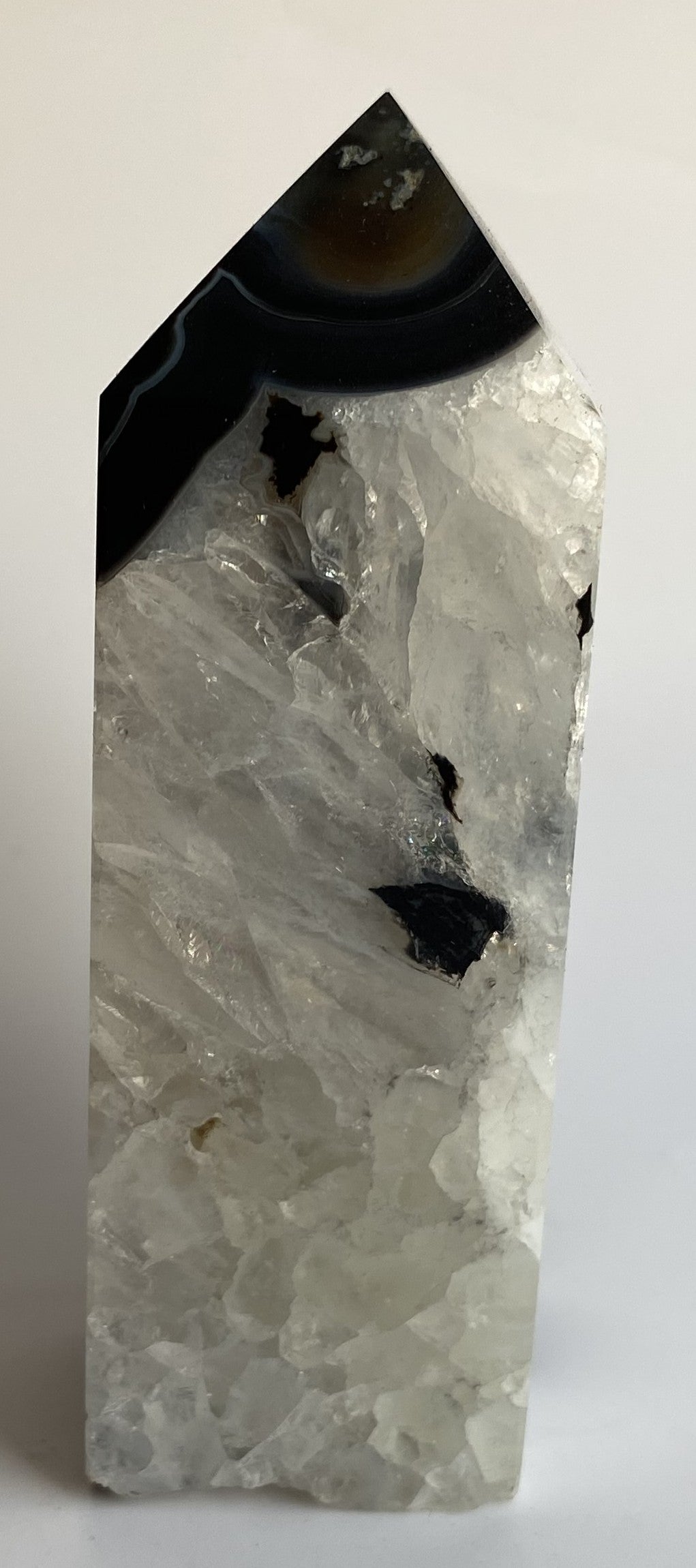 Obelisc din cristal de agat negru pe fundal alb sub lumina naturala