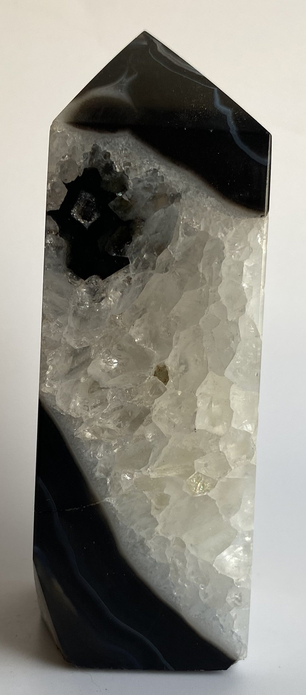 Obelisc din cristal de agat negru pe fundal alb sub lumina naturala