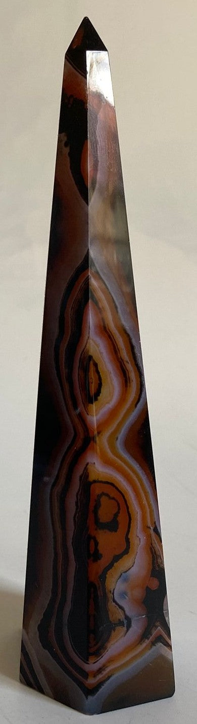 Obelisc piramidal din cristal de agat negru-rosu pe fundal alb