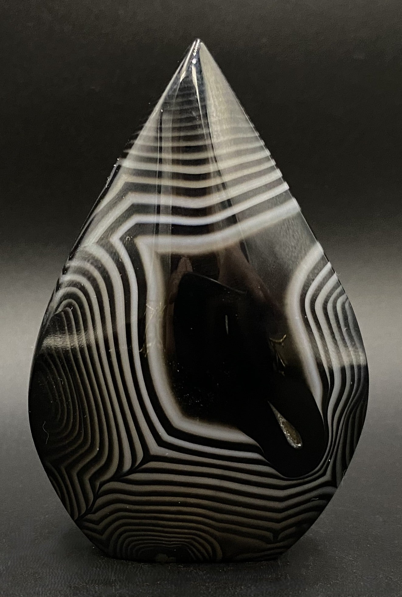 Sculptura din cristal de agat negru pe fundal negru sub lumina artificiala