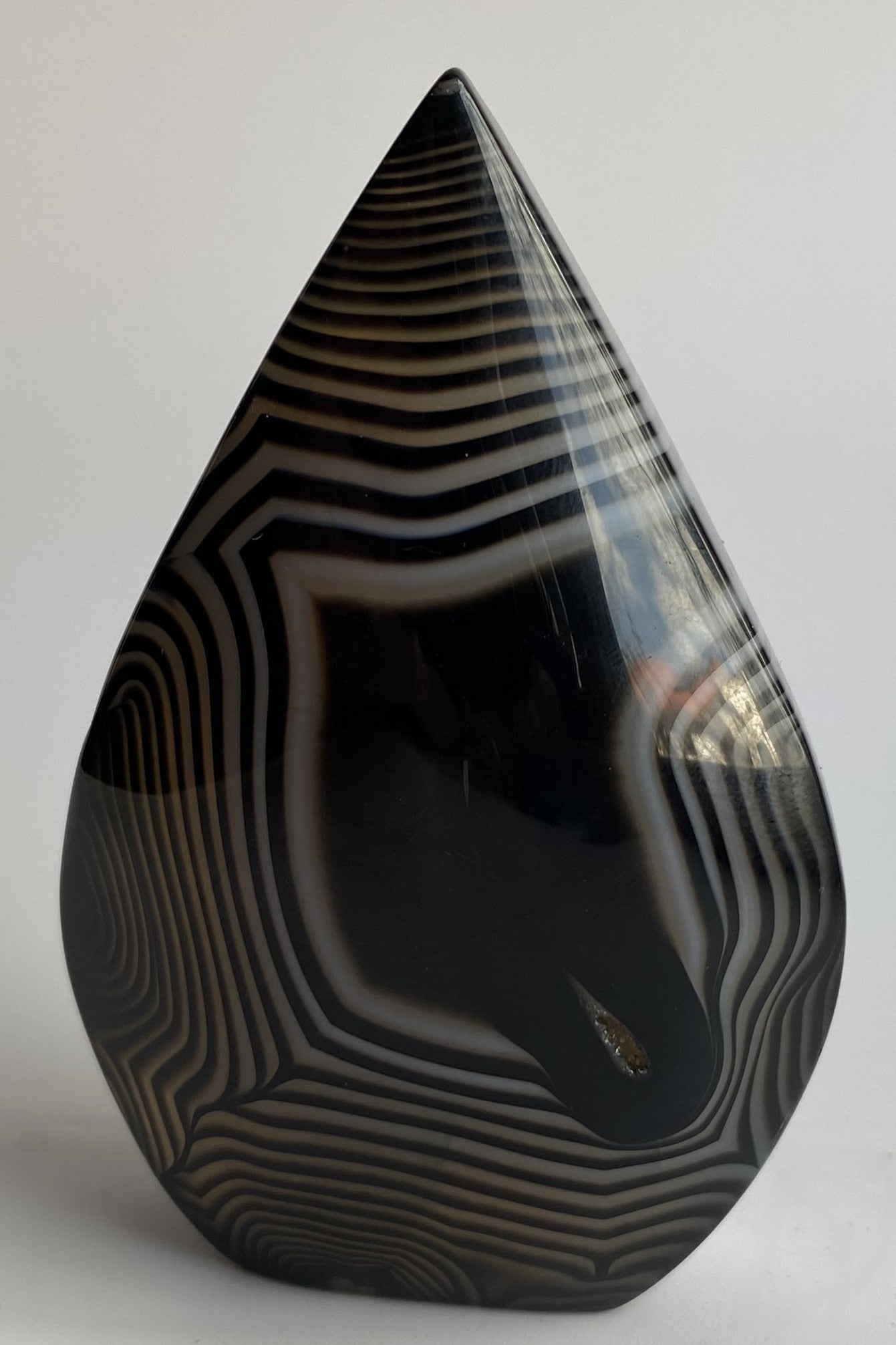 Sculptura din cristal de agat negru pe fundal alb sub lumina naturala