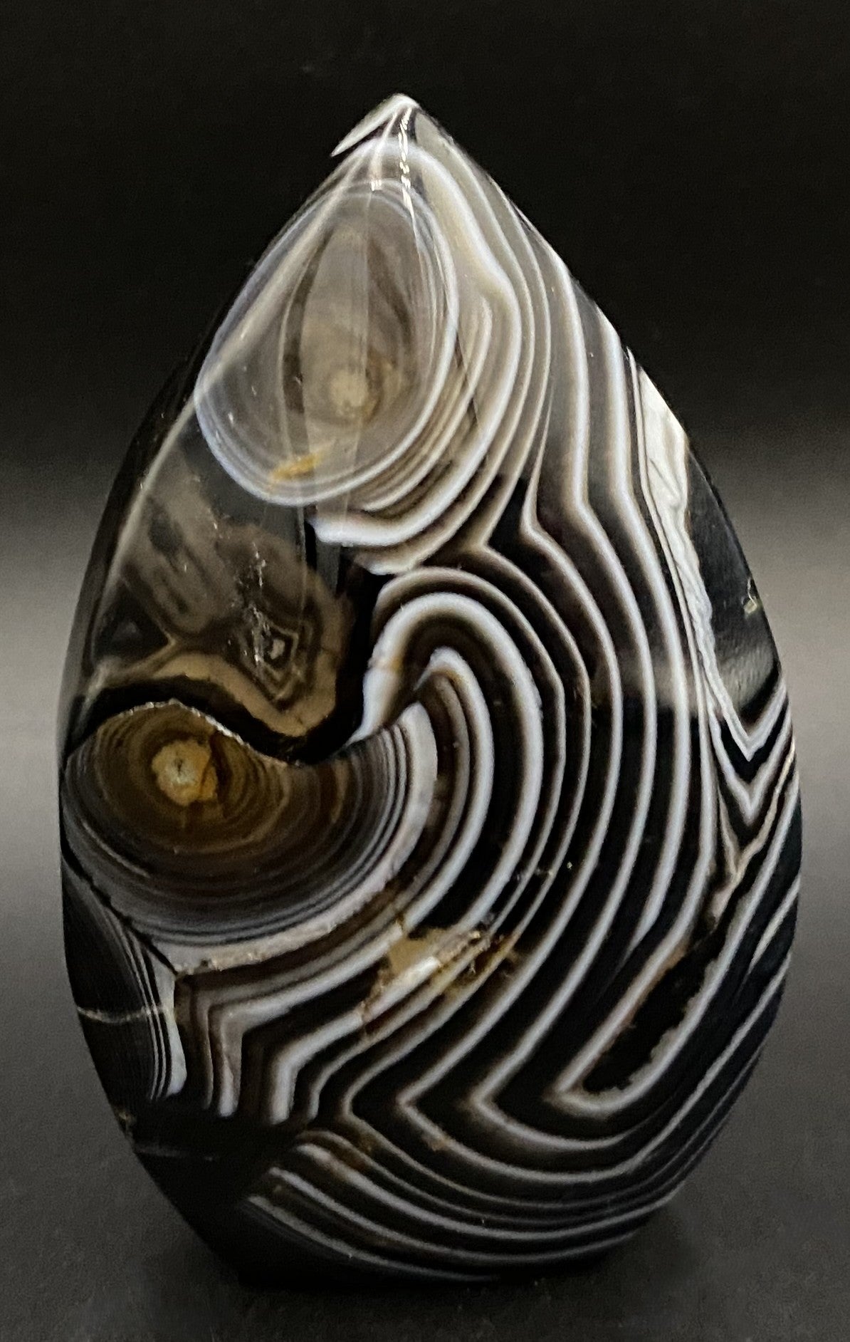 Sculptura din cristal de agat negru pe fundal negru sub lumina artificiala