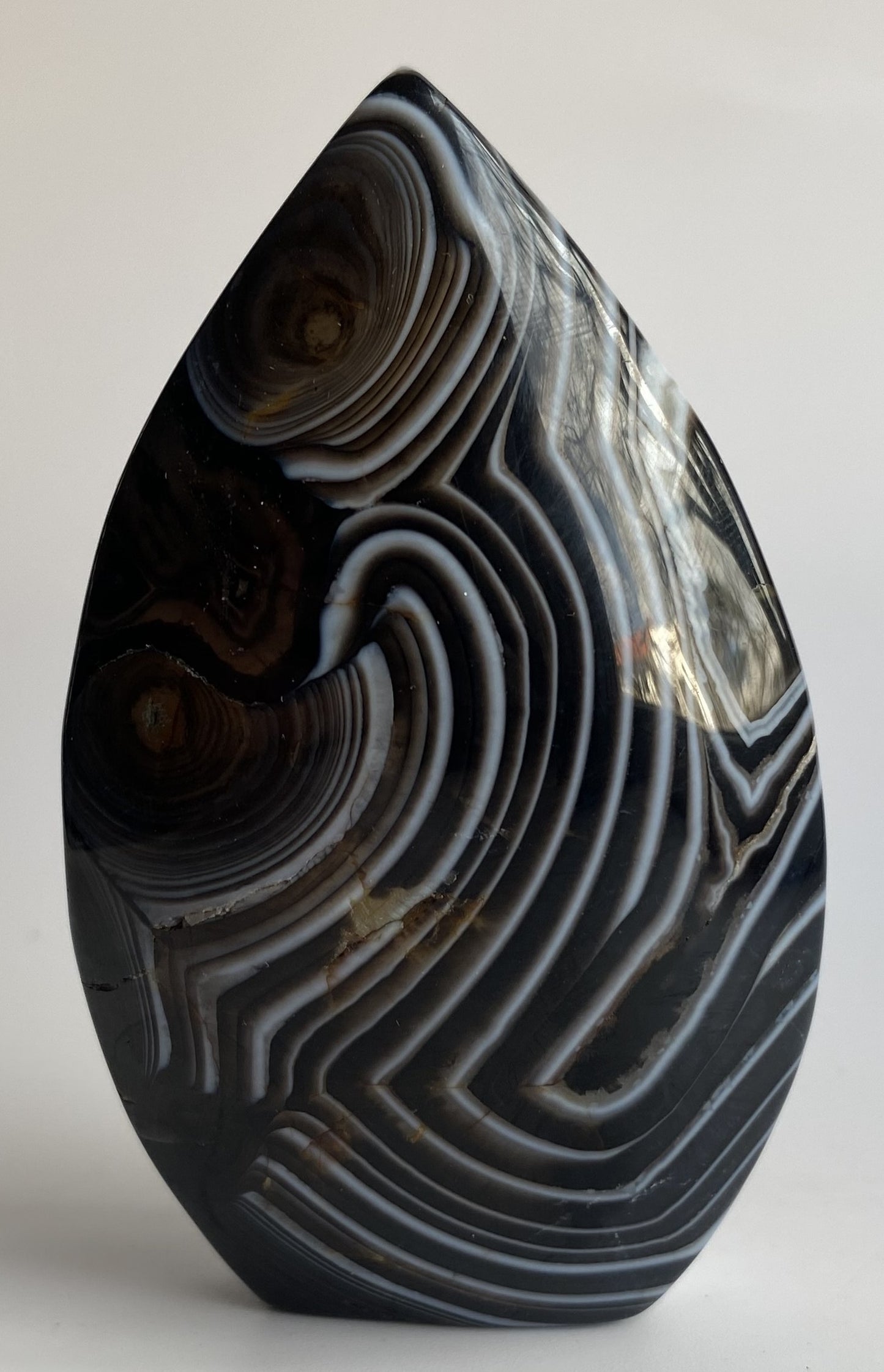 Sculptura din cristal de agat negru pe fundal alb sub lumina naturala