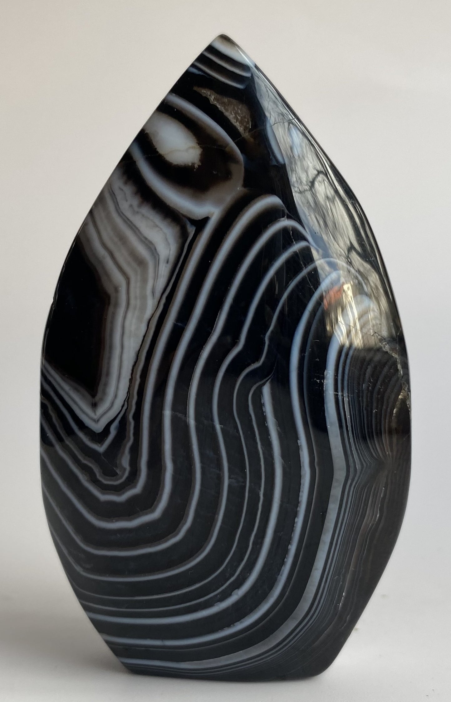 Sculptura din cristal de agat negru pe fundal alb sub lumina naturala