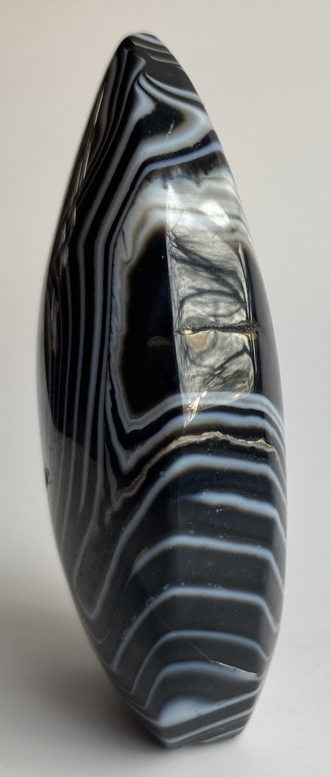 Sculptura din cristal de agat negru pe fundal alb sub lumina naturala