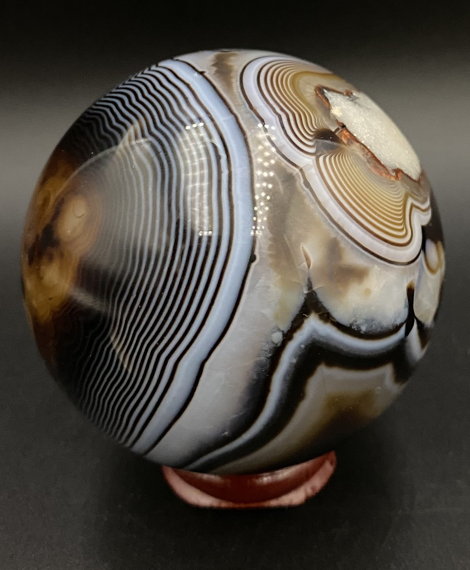 Sfera din cristal de agat negru pe fundal negru sub lumina artificiala