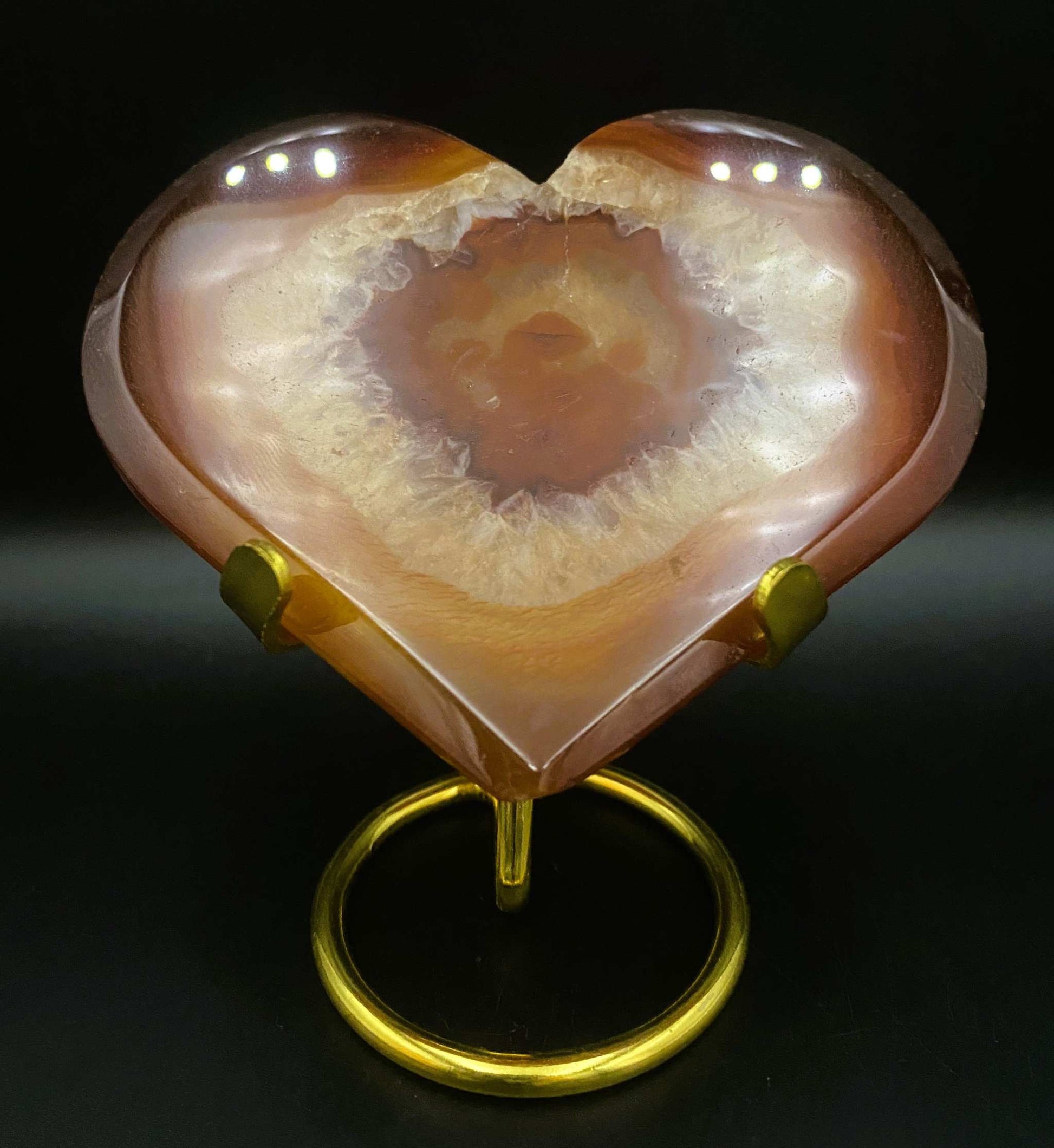 Heart-shaped red agate geode stone on metal stand