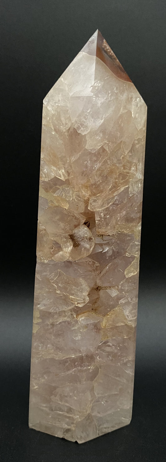 Obelisc din cristal de agat rosu pe fond negru sub lumina artificiala