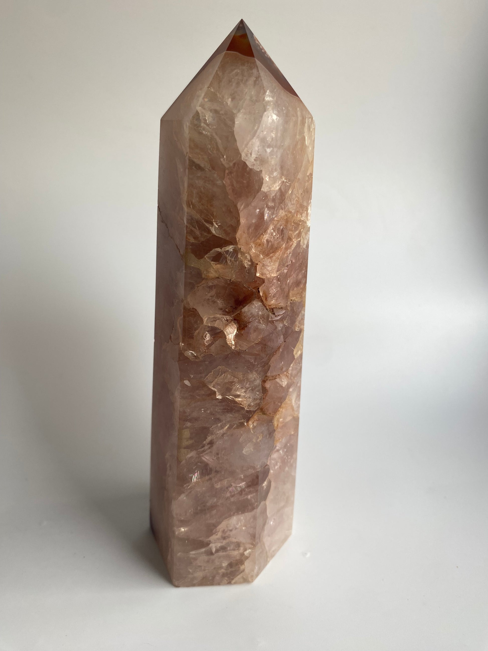 Obelisc din cristal de agat rosu pe fond alb sub lumina naturala