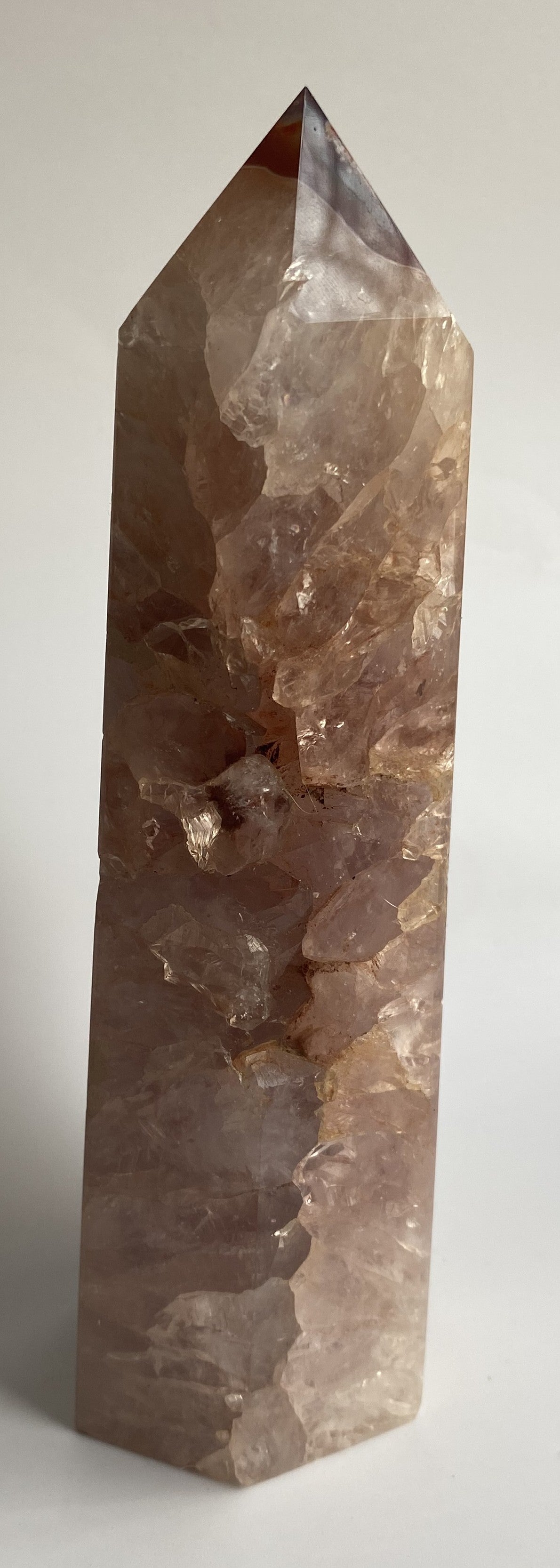 Obelisc din cristal de agat rosu pe fond alb sub lumina naturala