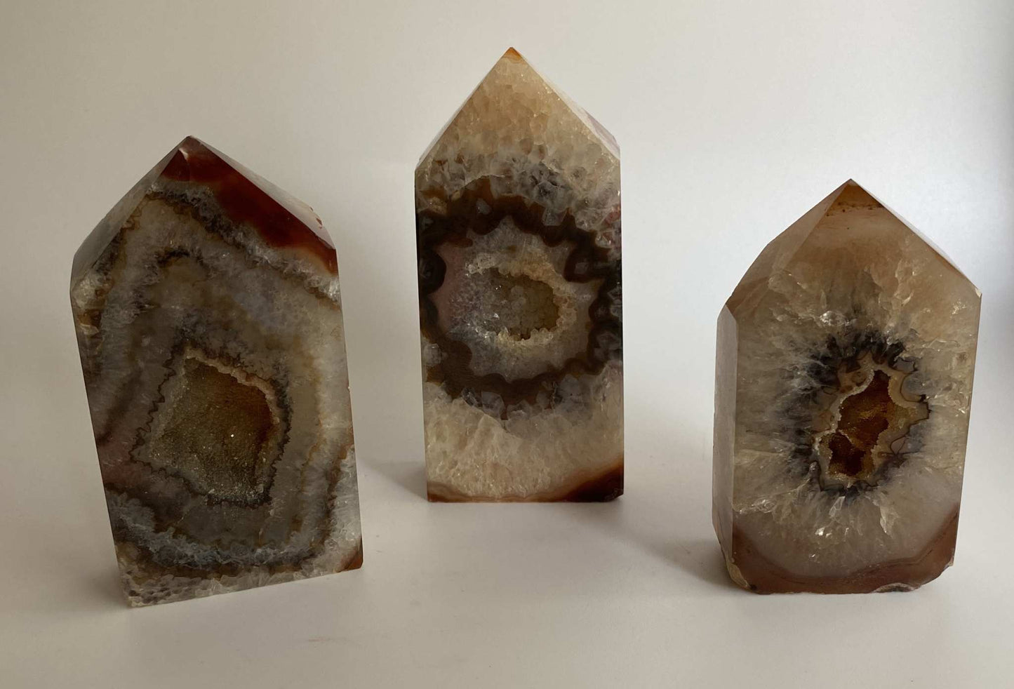 Set of three Agat Rosu gemstone obelisks from geode stone displayed on white background
