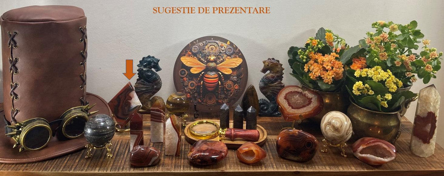 Romb din Agat Rosu cu suport metalic pe masa decorativa cu alte pietre semipretioase si flori.